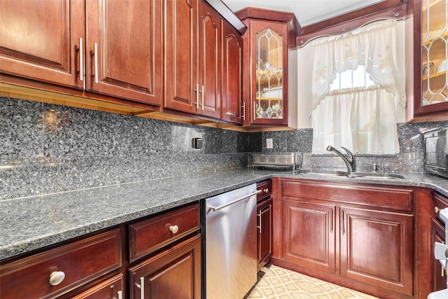 kitchen featuring a sink, stainless steel dishwasher, tasteful backsplash, dark stone countertops, and glass insert cabinets