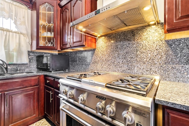 kitchen featuring dark brown cabinets, high end stove, under cabinet range hood, black microwave, and a sink