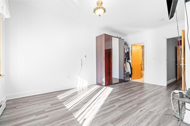 unfurnished room featuring baseboards, wood finished floors, and ornamental molding