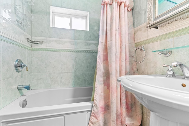 bathroom with shower / bath combo, a sink, and tile walls