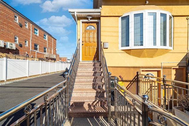 doorway to property with fence and stucco siding