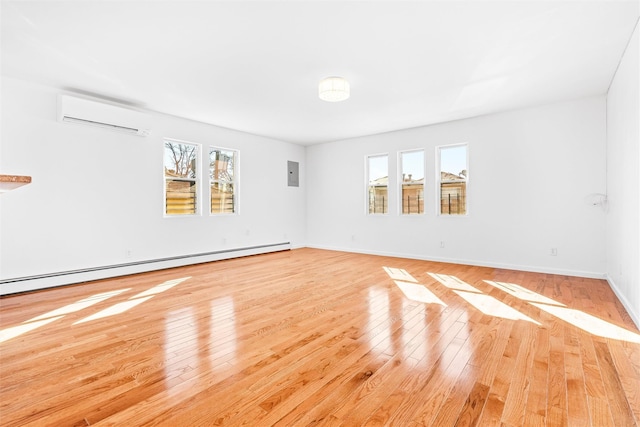 spare room with light wood-type flooring, a wall mounted air conditioner, a baseboard radiator, and electric panel