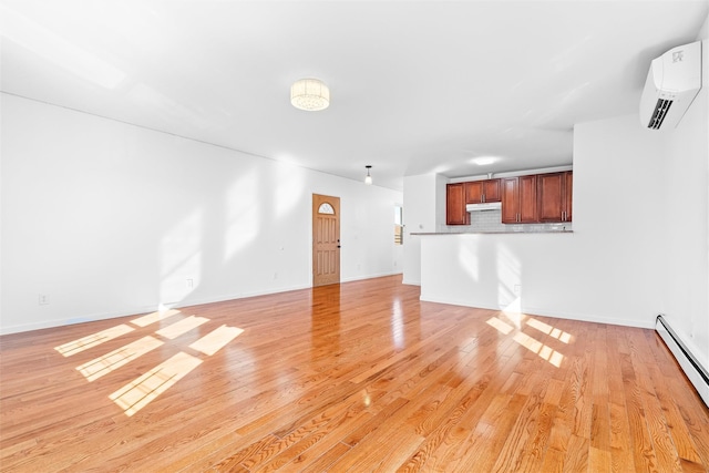 unfurnished living room with a baseboard heating unit, baseboards, a wall mounted air conditioner, and light wood finished floors