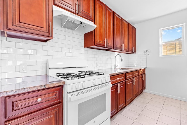 kitchen featuring backsplash, white gas range oven, a sink, and under cabinet range hood