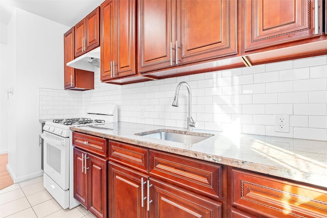 kitchen featuring light stone counters, light tile patterned flooring, a sink, white range with gas stovetop, and under cabinet range hood