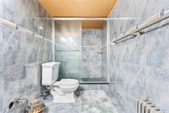 bathroom with toilet, a stall shower, tile walls, and radiator