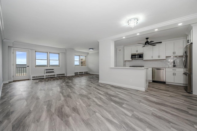 interior space with tasteful backsplash, open floor plan, light countertops, stainless steel appliances, and crown molding