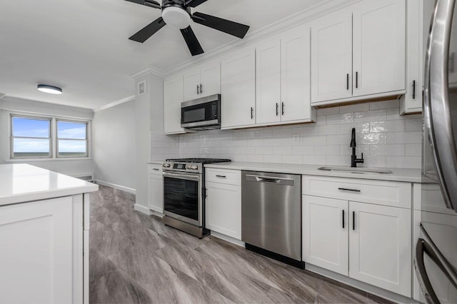 kitchen with appliances with stainless steel finishes, ornamental molding, a sink, light countertops, and backsplash