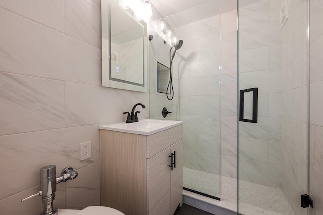 bathroom with a stall shower, vanity, and tile walls