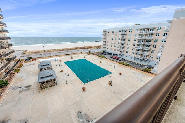 view of swimming pool featuring a water view and a beach view