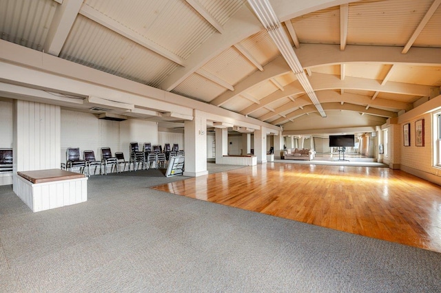 interior space with carpet, lofted ceiling with beams, and wood finished floors