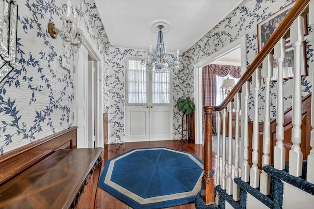 foyer with wood finished floors, stairway, an inviting chandelier, and wallpapered walls