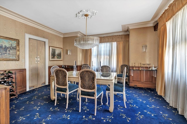 dining space featuring a wainscoted wall, ornamental molding, carpet flooring, and wallpapered walls