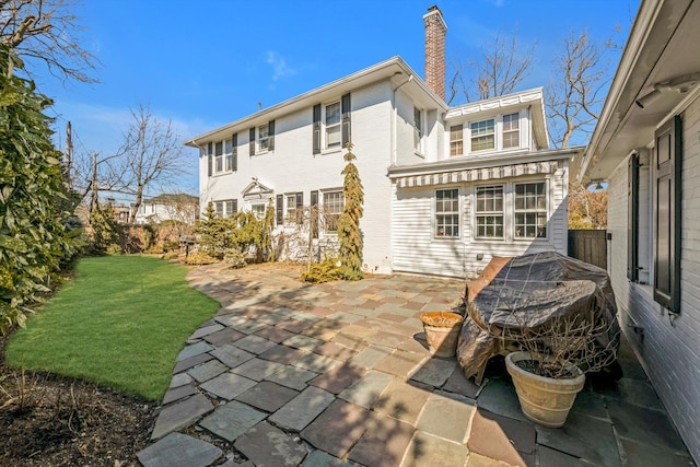 back of house featuring a patio area, a chimney, and a yard