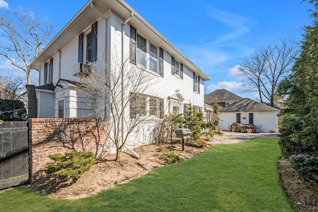 exterior space featuring an outbuilding, a patio area, a lawn, and brick siding