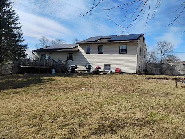 back of property with solar panels, a yard, fence, and a wooden deck