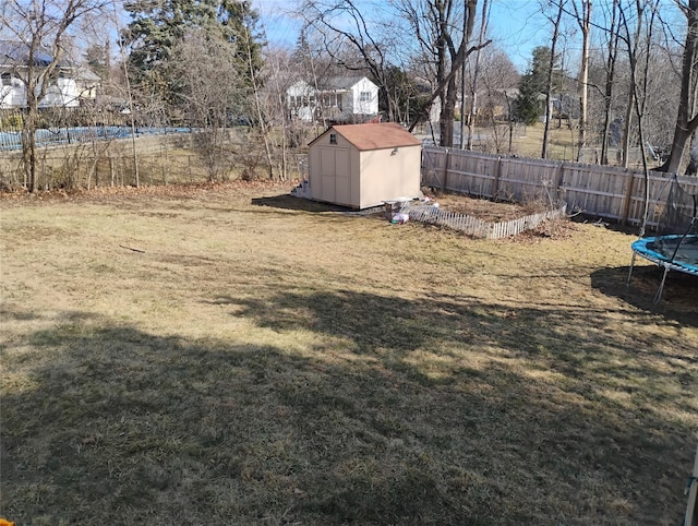 view of yard featuring a fenced backyard, an outbuilding, a trampoline, and a storage shed