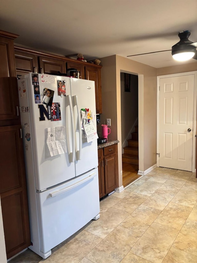 kitchen featuring light stone counters, baseboards, and white refrigerator with ice dispenser