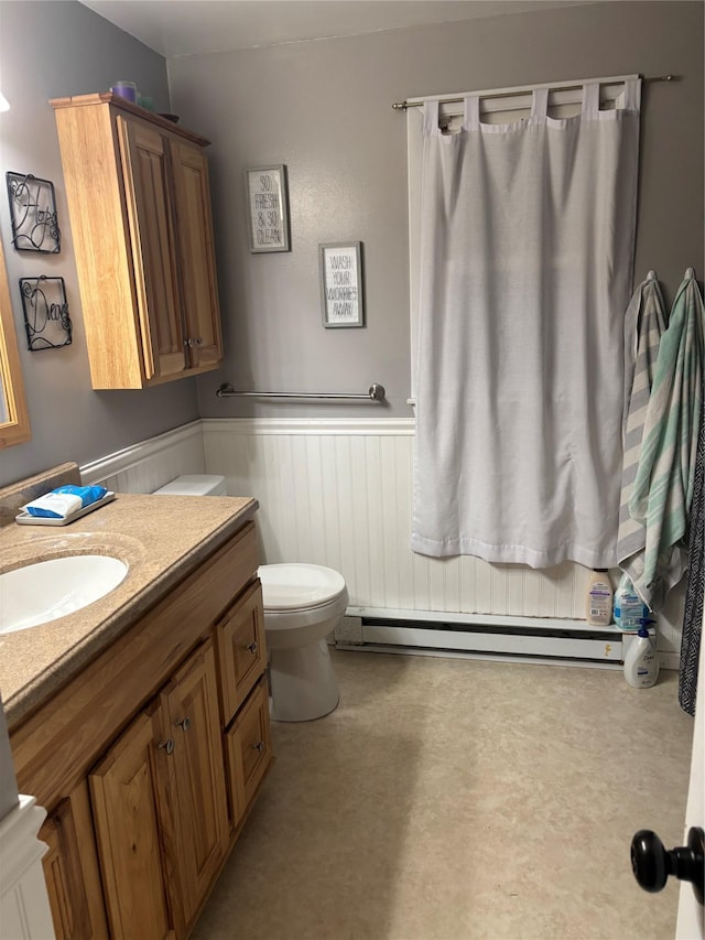 bathroom featuring a wainscoted wall, toilet, vanity, and a baseboard radiator