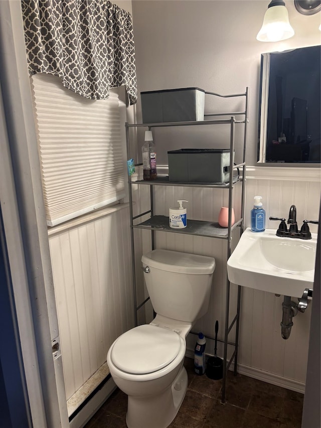 bathroom featuring tile patterned flooring, a wainscoted wall, toilet, and a sink