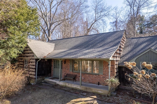 view of front of home featuring a shingled roof and brick siding