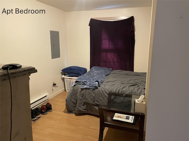 bedroom featuring a baseboard heating unit, electric panel, baseboards, and wood finished floors