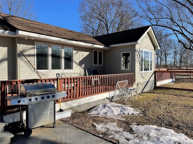 exterior space with a deck and roof with shingles