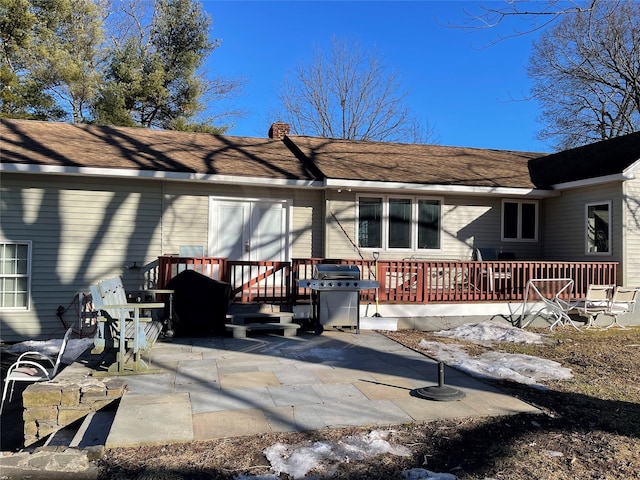 rear view of property featuring a deck, a patio area, and a chimney