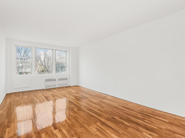 empty room with radiator and hardwood / wood-style floors