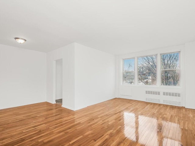 empty room with radiator heating unit and hardwood / wood-style flooring