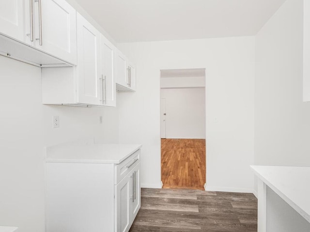 kitchen with white cabinets, light countertops, dark wood finished floors, and baseboards