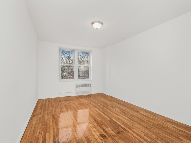 empty room with radiator heating unit and hardwood / wood-style flooring