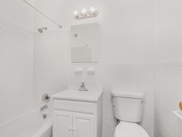 bathroom featuring toilet, tub / shower combination, tile walls, and vanity