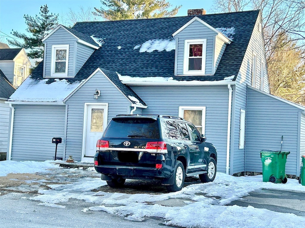 view of front of home with a shingled roof and a chimney