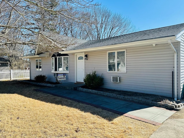 ranch-style house featuring fence, a front lawn, and roof with shingles