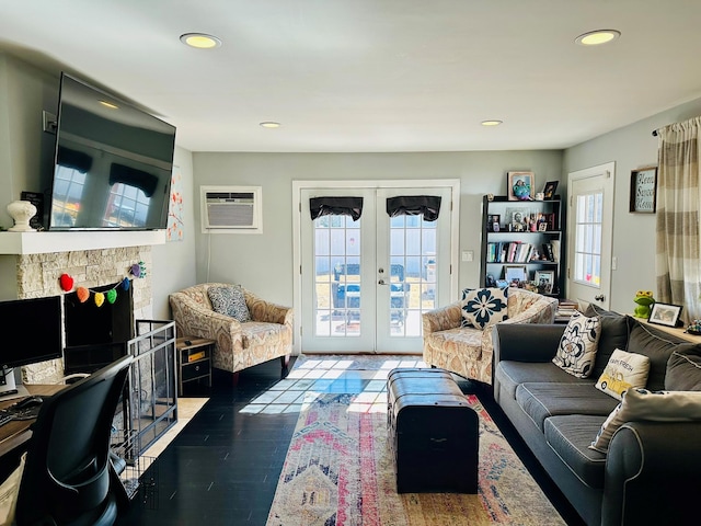 living area with french doors, a wall mounted air conditioner, wood finished floors, and a healthy amount of sunlight