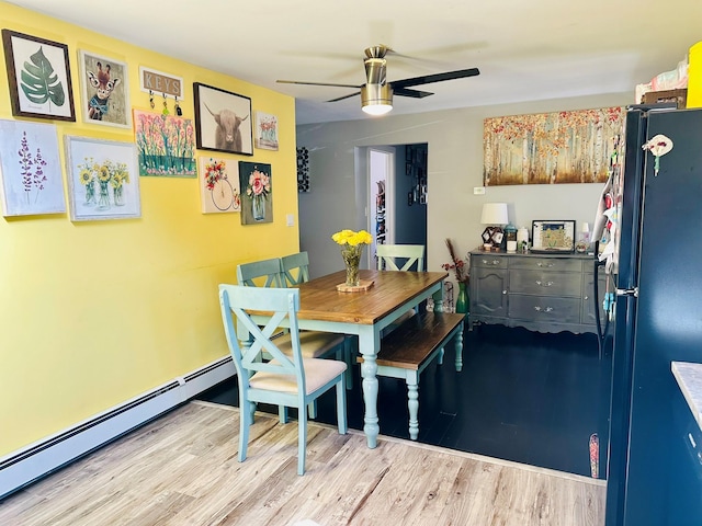 dining area with ceiling fan, a baseboard radiator, and light wood-style floors