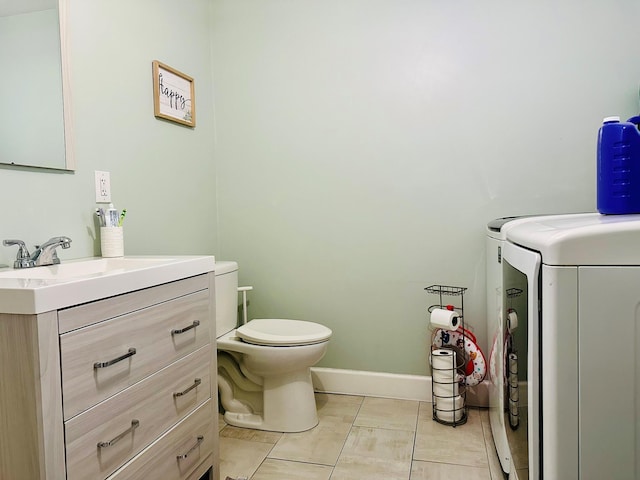 half bathroom with washing machine and dryer, baseboards, vanity, and toilet