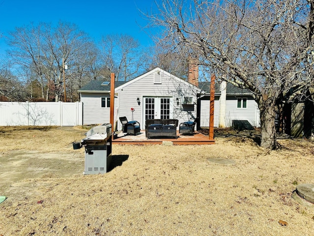 back of property with french doors, a wooden deck, and fence