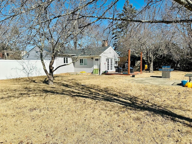 ranch-style house with a chimney, fence, a deck, and a front yard