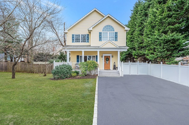 view of front of home featuring a porch, a front yard, driveway, and fence