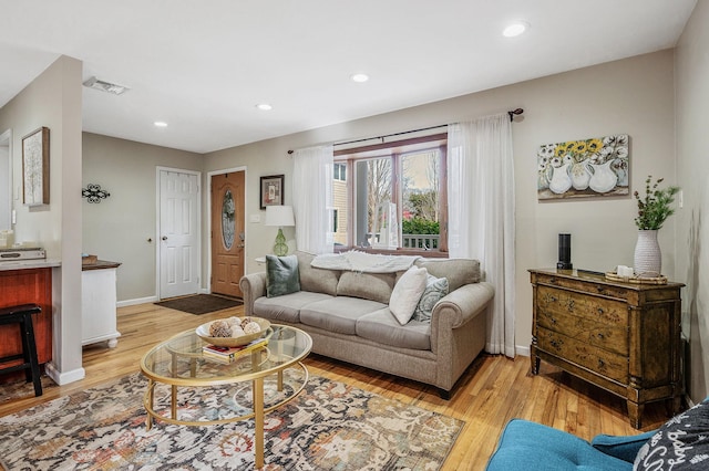 living room with light wood-style flooring, visible vents, baseboards, and recessed lighting