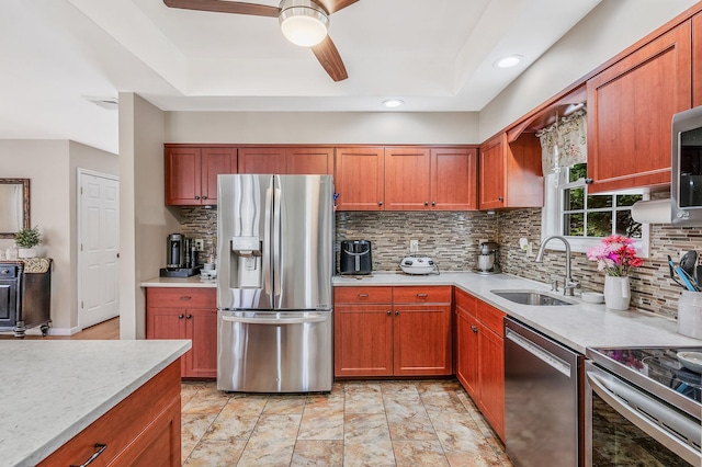 kitchen with stainless steel appliances, a sink, a ceiling fan, light countertops, and backsplash