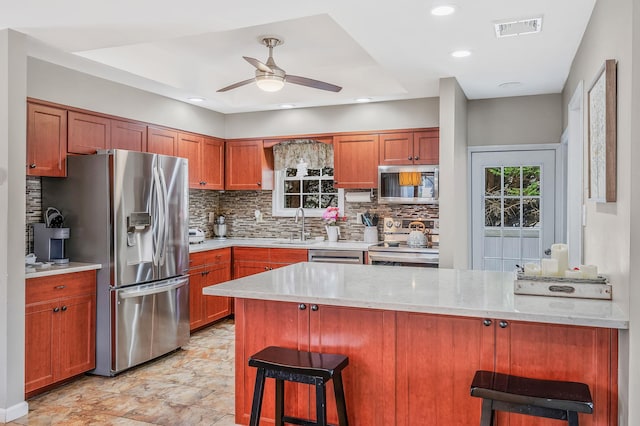 kitchen with visible vents, a kitchen breakfast bar, a peninsula, stainless steel appliances, and a sink