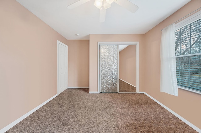 unfurnished bedroom featuring carpet, baseboards, ceiling fan, and a closet