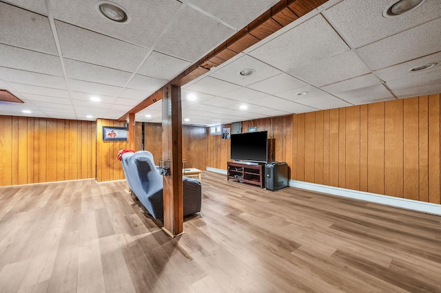 interior space featuring wood walls, wood finished floors, a paneled ceiling, and baseboards