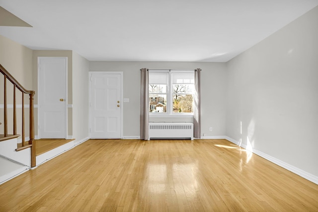 entryway featuring light wood-type flooring, radiator, stairway, and baseboards