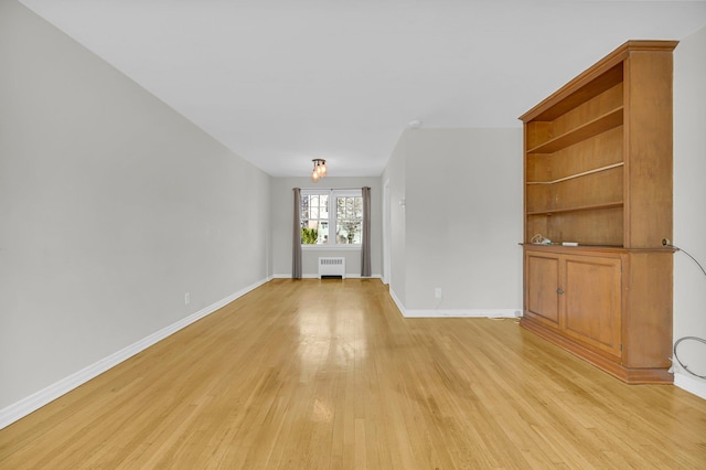 unfurnished living room featuring light wood-style floors, radiator heating unit, and baseboards