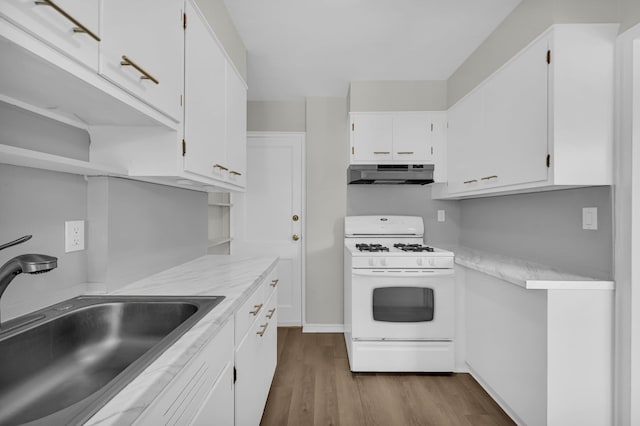 kitchen with a sink, under cabinet range hood, light countertops, and gas range gas stove