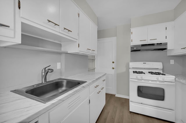 kitchen with white gas range oven, white cabinets, light countertops, under cabinet range hood, and a sink